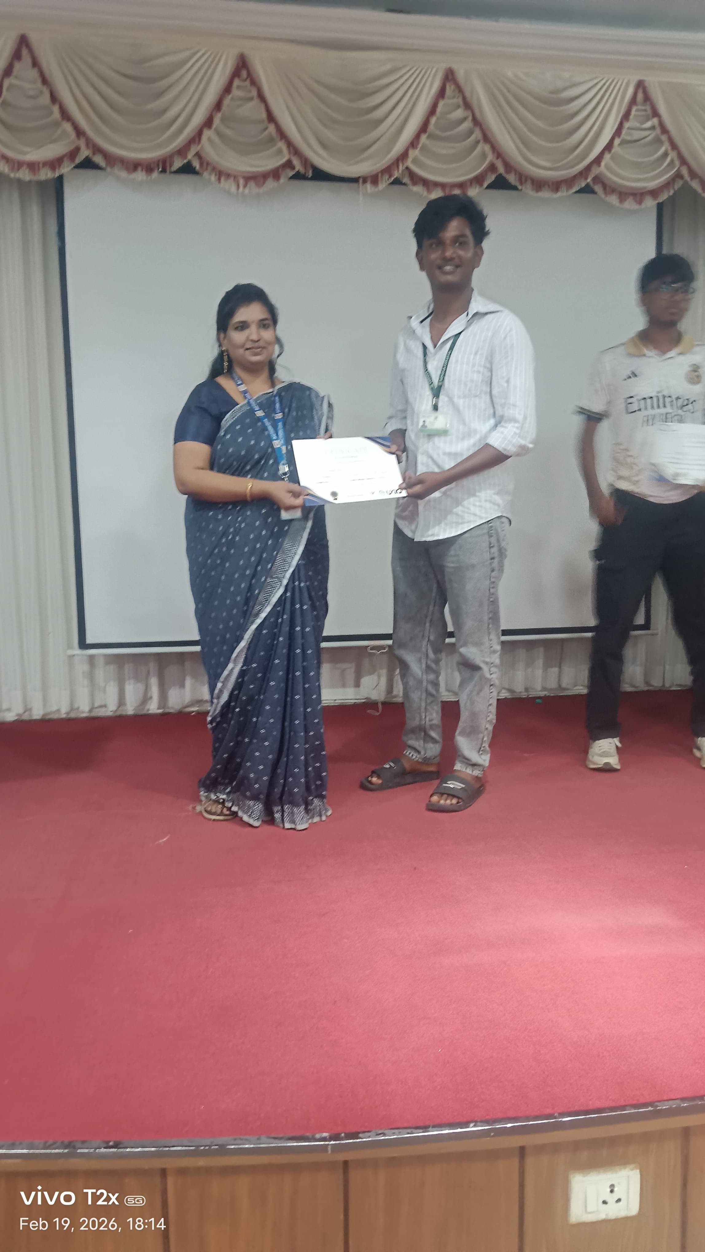 Student receiving a certificate on a college auditorium stage