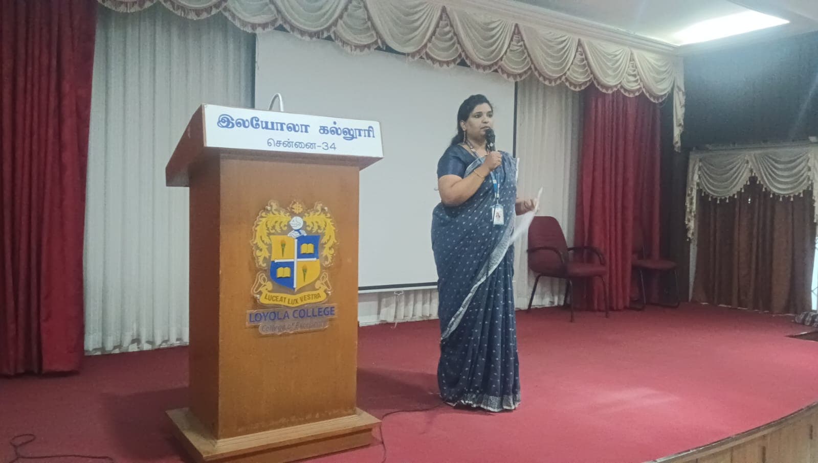 Facilitator speaking at a college auditorium podium