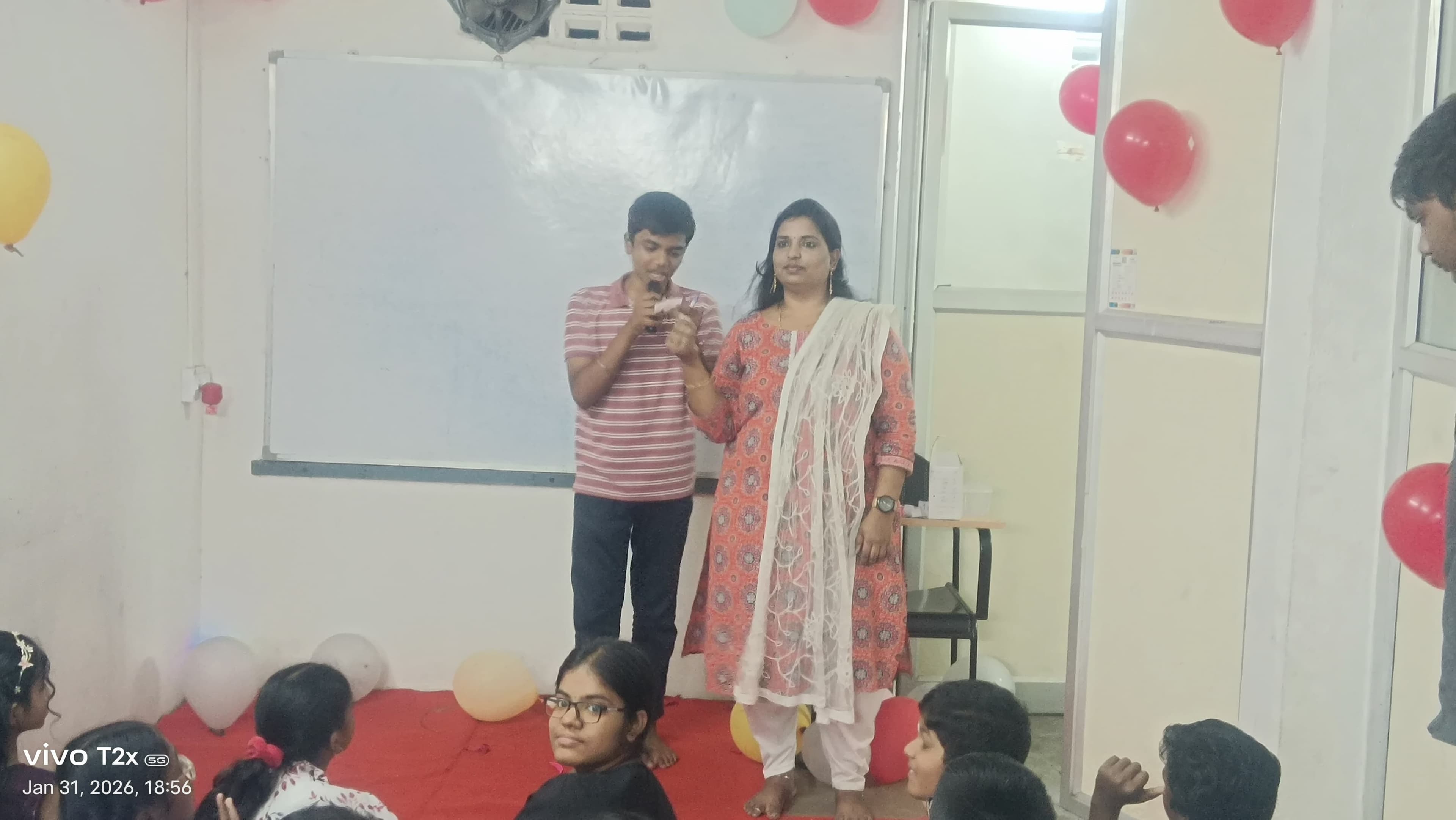 Facilitator and student engaging in an activity at a balloon-decorated event