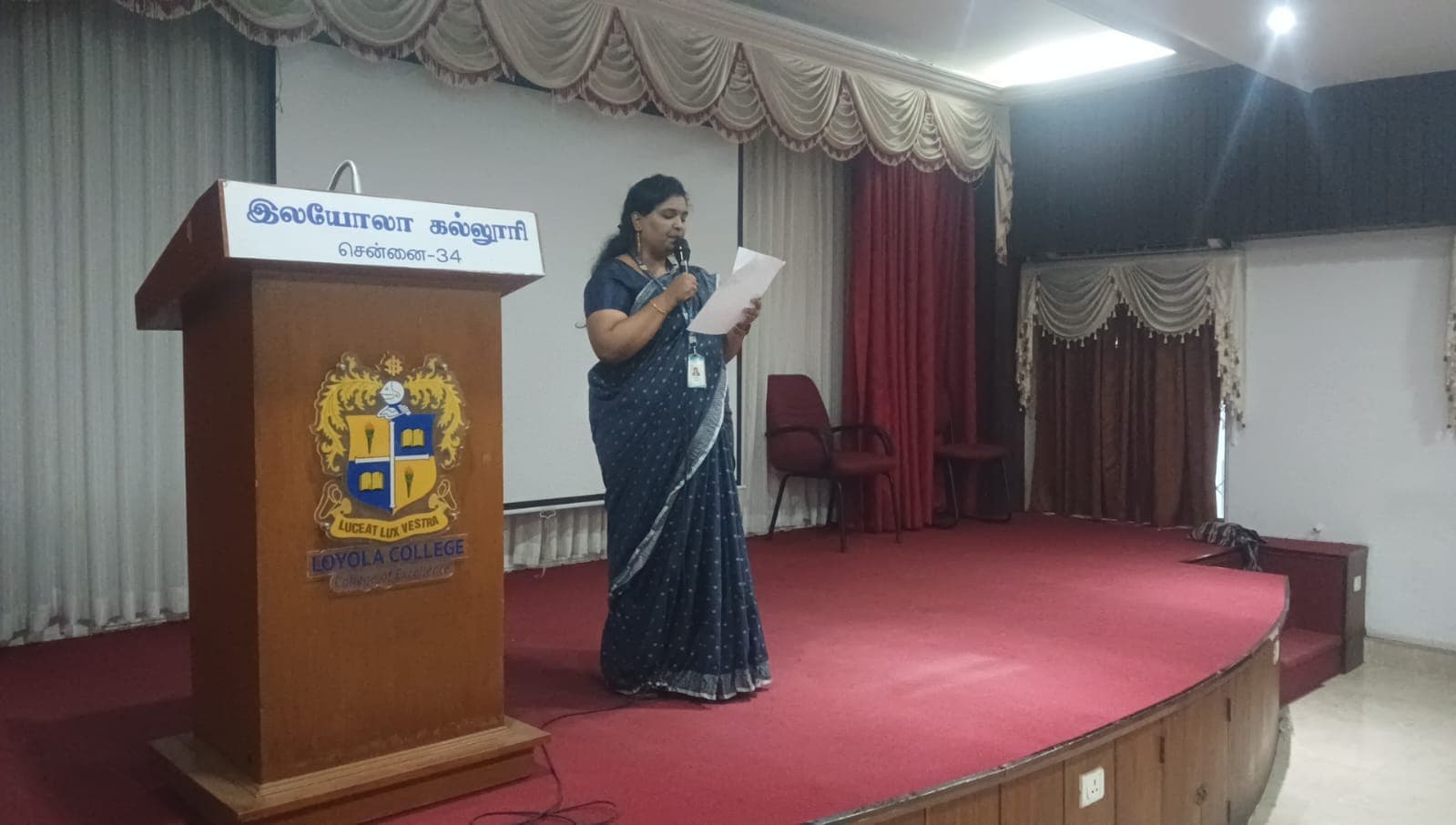 Facilitator speaking at a college auditorium podium