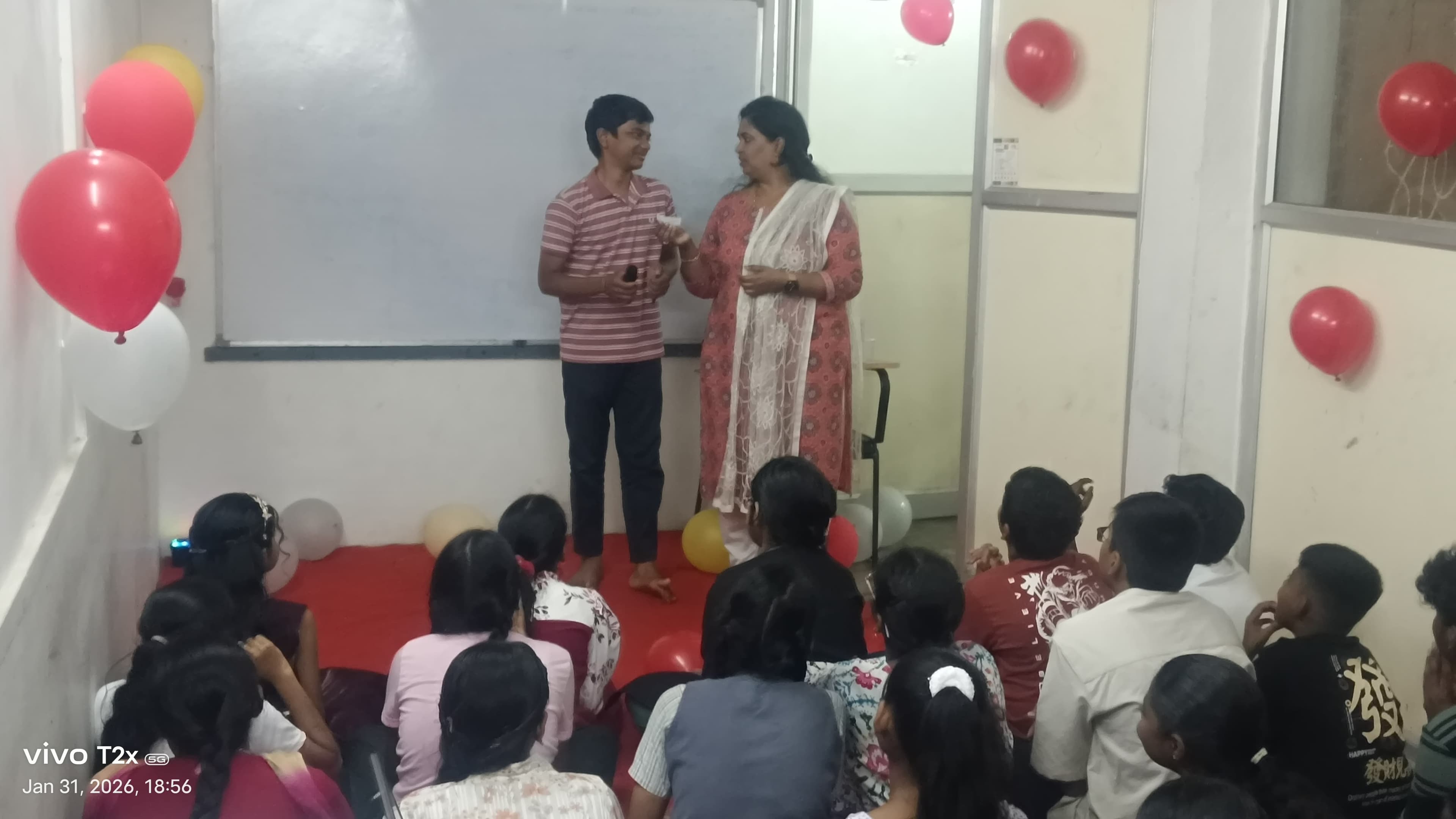 Facilitator and participant in conversation at a balloon-decorated event