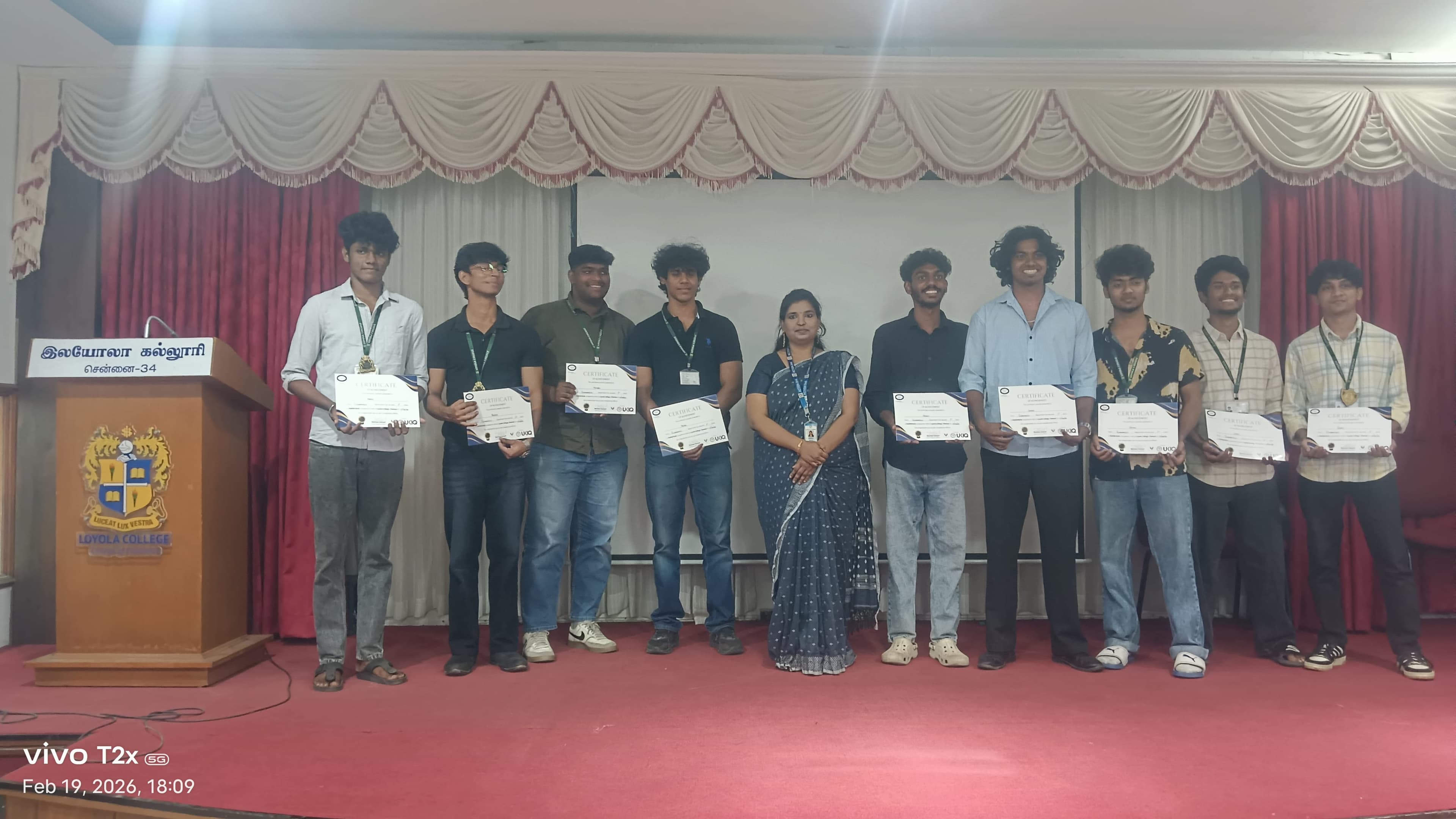 Row of college students holding certificates on an auditorium stage