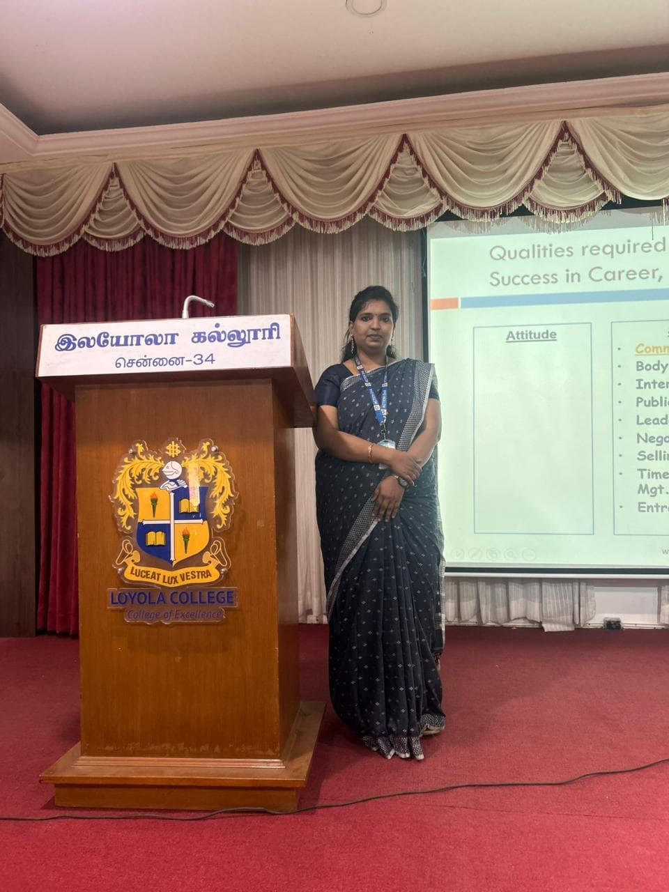 Facilitator standing at a college auditorium podium beside a career-skills presentation