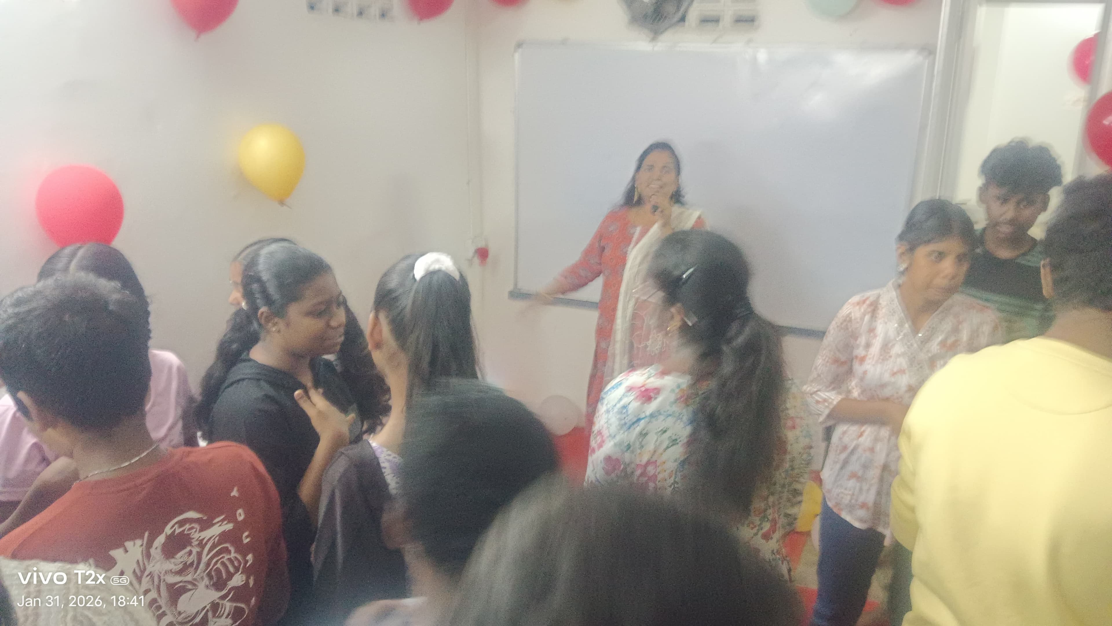 Facilitator addressing a group of students at a balloon-decorated event