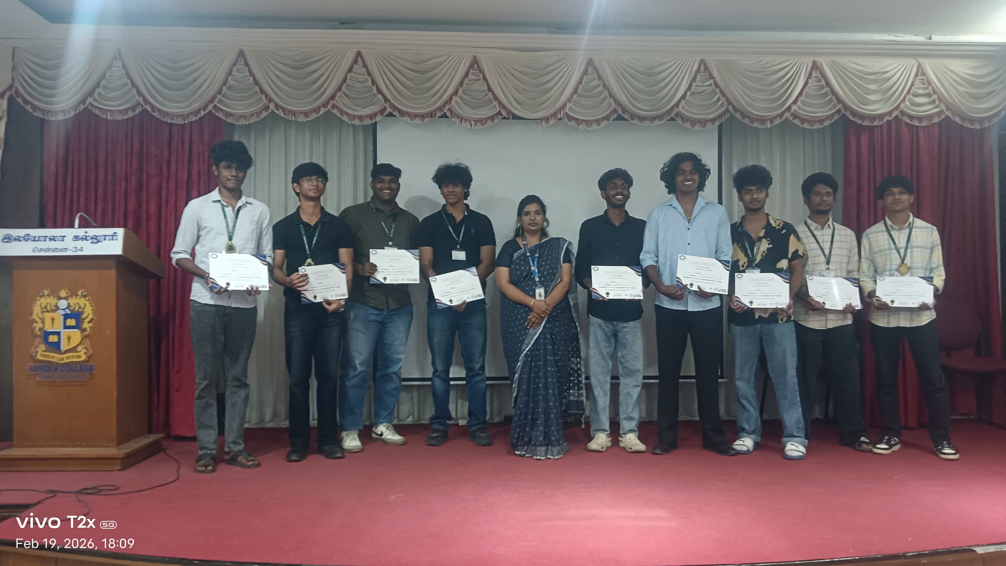 Row of college students holding certificates on an auditorium stage