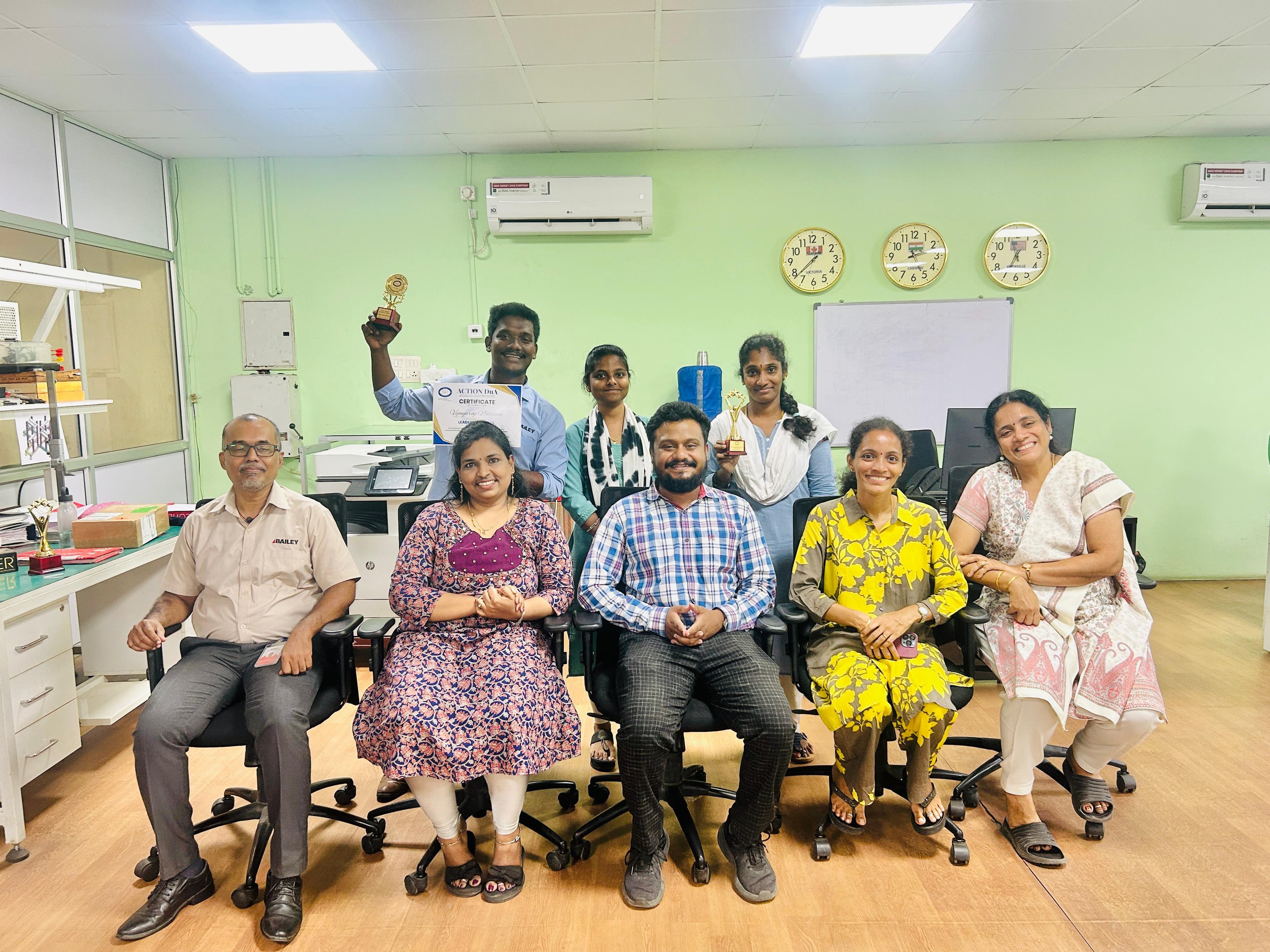 Corporate team posing with trophies and a certificate in an office