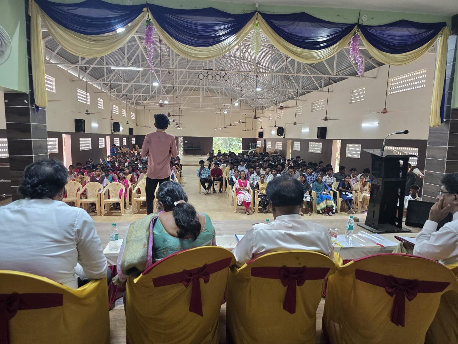 Facilitator addressing hundreds of students seated in a college auditorium
