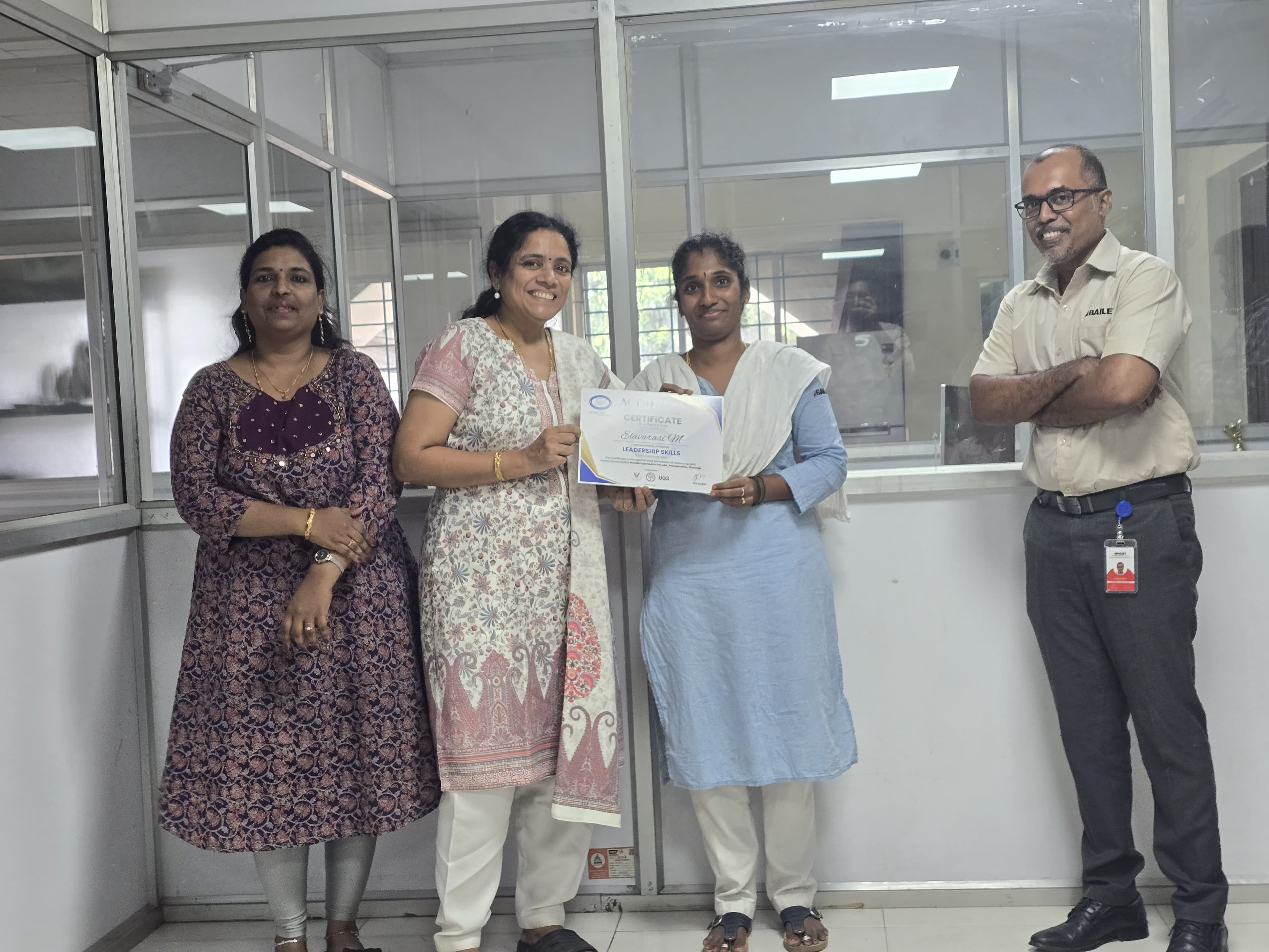 Corporate team presenting a leadership skills certificate in a glass-walled office
