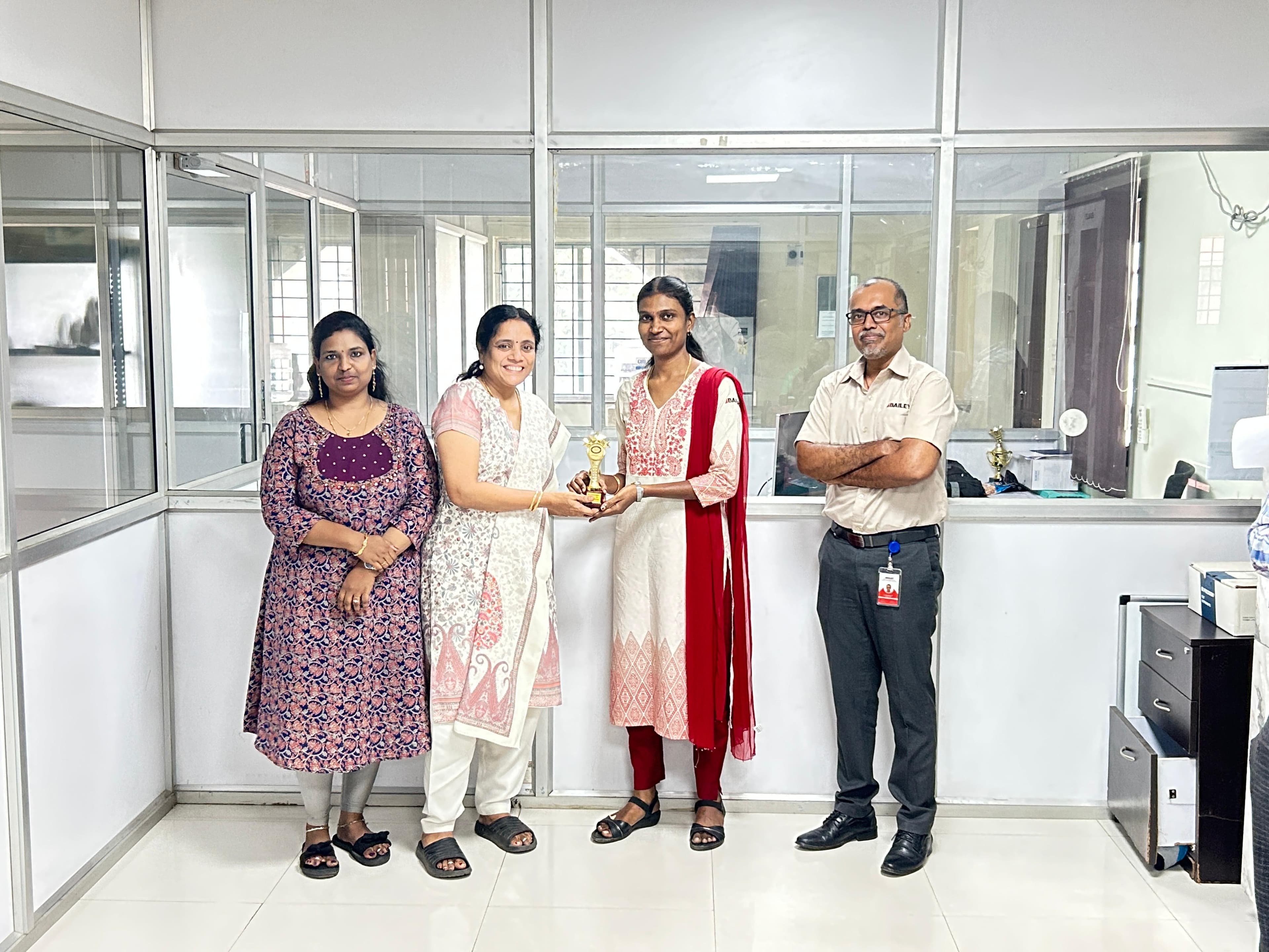 Corporate team posing with a trophy in a glass-walled office