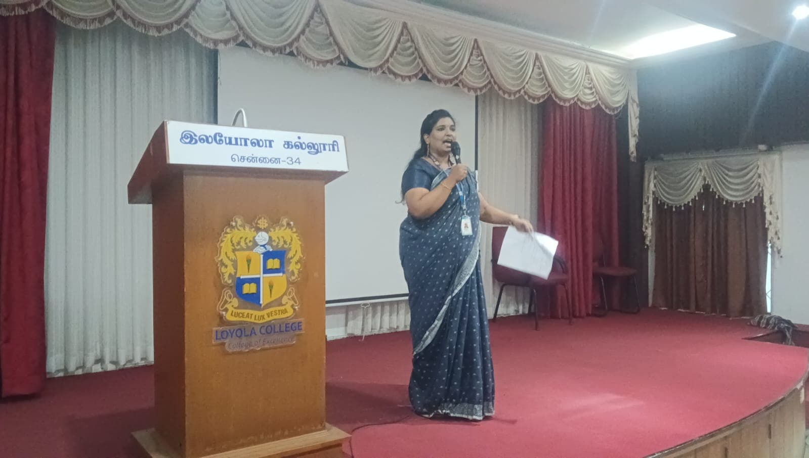 Facilitator speaking at a college auditorium podium