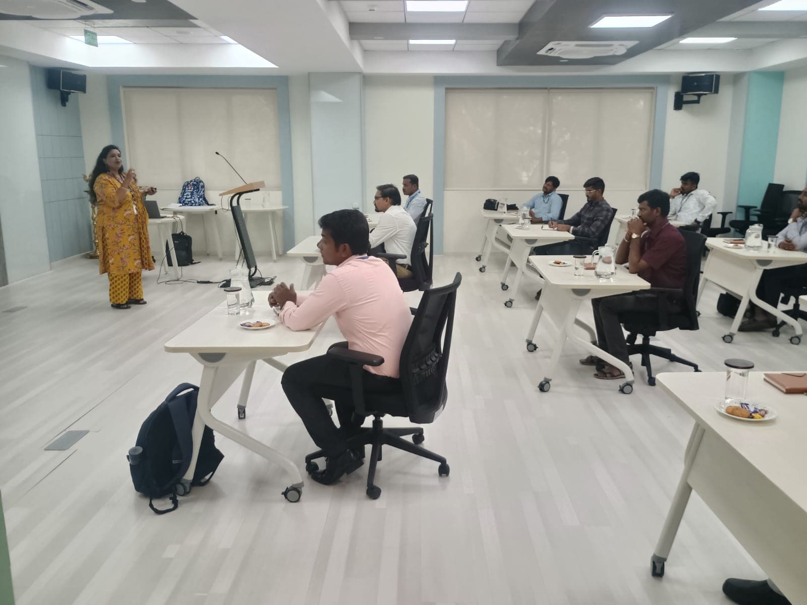 Trainer addressing a seated group in a modern office training room