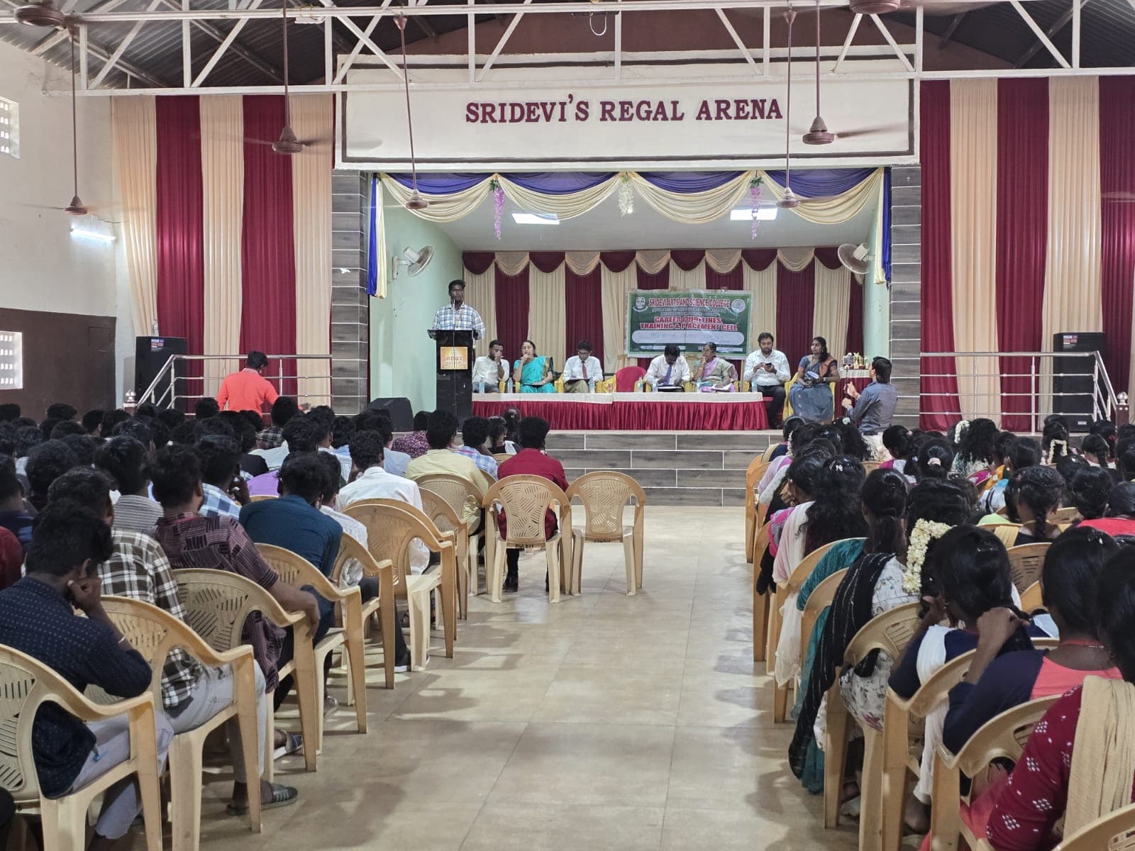 Speaker addressing students from a stage at a college placement cell event