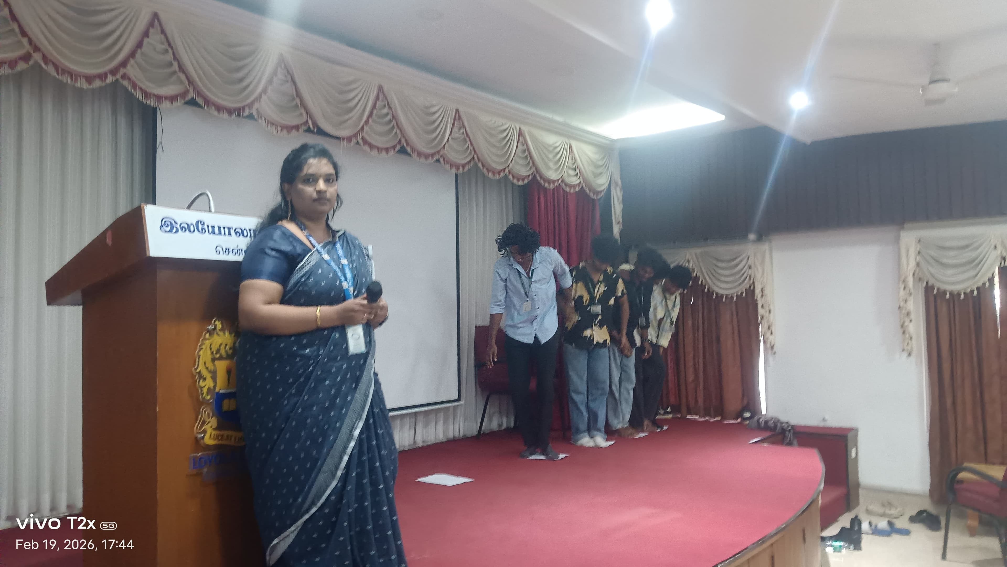 Facilitator on stage with a line of students at a college event