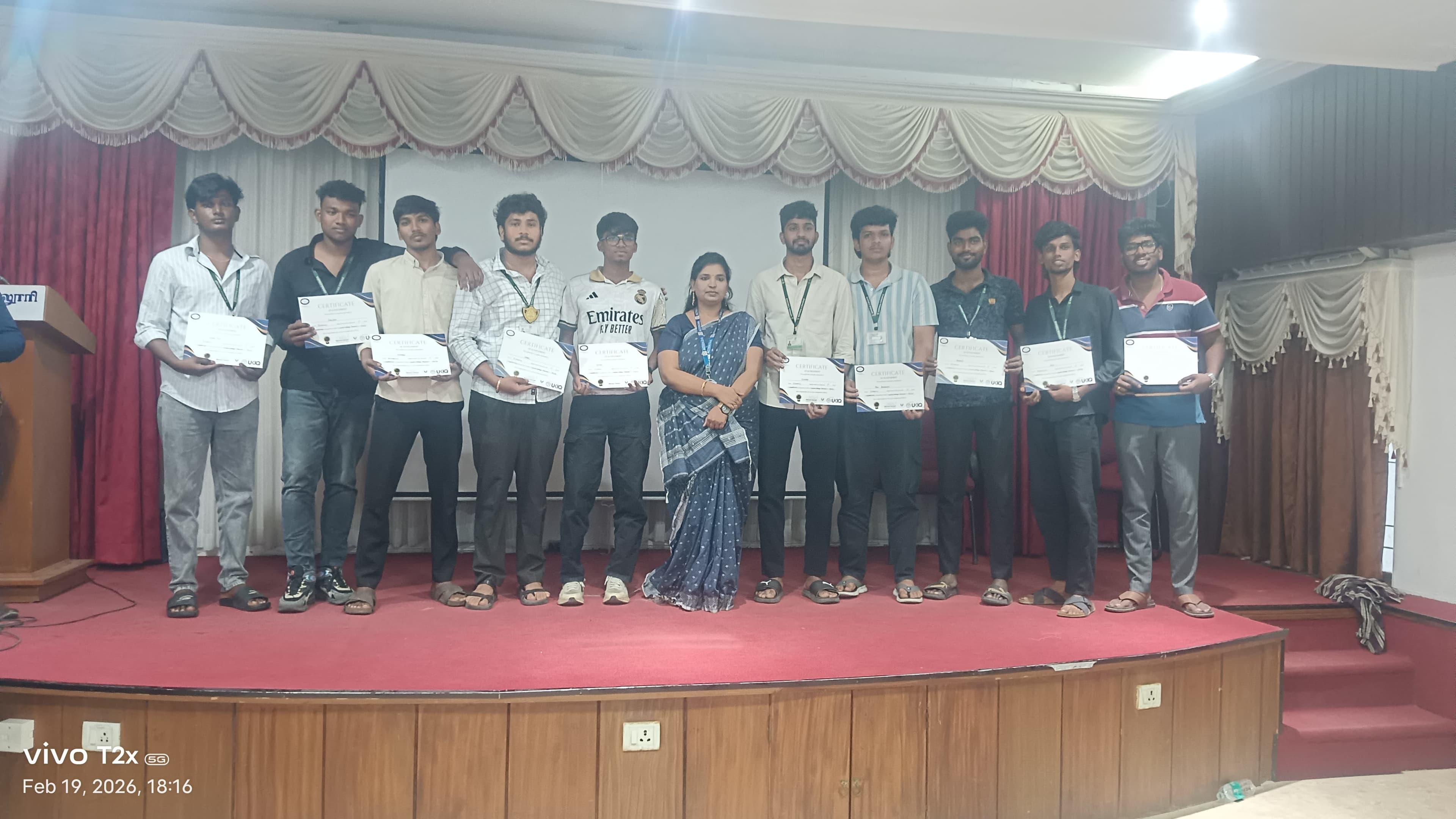 Row of college students holding certificates on an auditorium stage